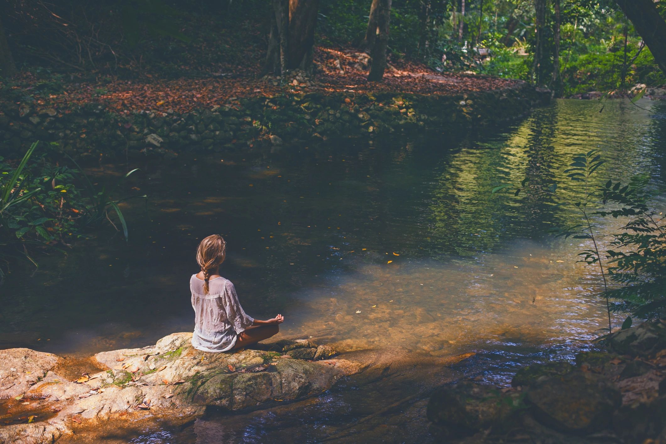 Woman in contemplative peace by a forest stream